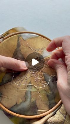 two hands are stitching together fabric to make a handbag with spider webs on it