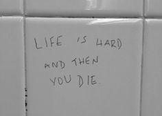 a white tile wall with writing on it that says life is hard and then you die