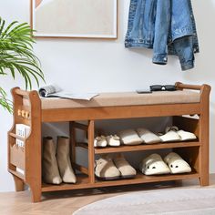 a wooden shoe rack filled with shoes next to a potted plant and coat rack