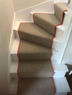 a carpeted staircase with an orange strip on the bottom