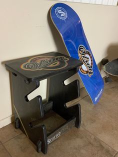 a blue snowboard sitting on top of a black stool next to a skateboard