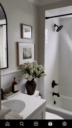 a vase with flowers is sitting on the counter in front of a sink and shower