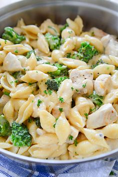 a bowl filled with pasta and broccoli on top of a blue and white towel