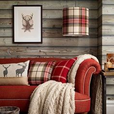 a living room filled with furniture next to a wall covered in wood planks and plaid pillows