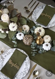 the table is set with green napkins, white plates and gold place settings for thanksgiving dinner