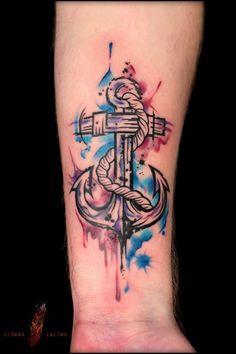 an anchor tattoo on the ankle with paint splatters and watercolor splashs