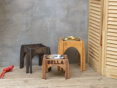 two wooden stools and a dog bowl on the floor in front of a wall