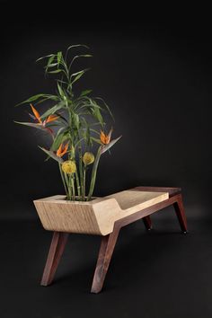 a planter with flowers in it sitting on a wooden stand against a black background