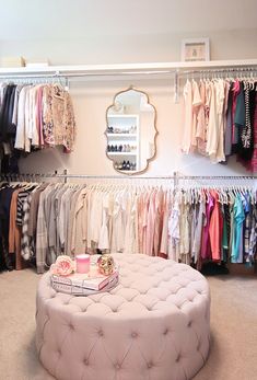 a white ottoman sitting in front of a closet filled with clothes