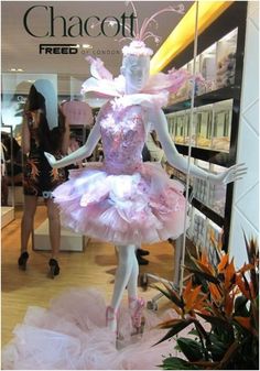 a mannequin dressed in pink and white is on display at a store window