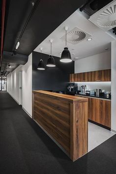 an office with black and white walls, wooden counter top and lights hanging from the ceiling