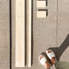 a person standing next to a piece of wood with the letter e on it's side