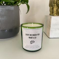 a green candle sitting on top of a table next to a potted plant and an elephant figurine