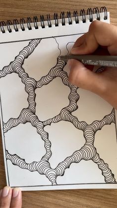 someone is drawing an intricate design on a piece of paper with a marker and pen