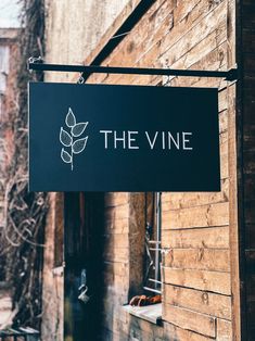 a sign hanging from the side of a building that says, the vine on it