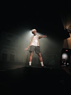 a man standing on top of a stage in front of a camera holding a cell phone