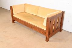 a wooden couch sitting on top of a cement floor next to a white brick wall