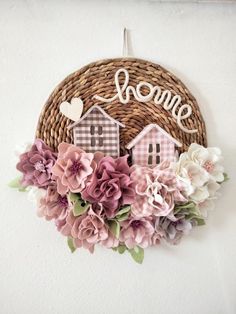 a basket with some flowers hanging on the wall next to a sign that says home