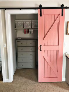 a pink barn door is open to reveal the bedroom's storage area and closet