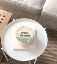 a birthday cake sitting on top of a white table next to a chair and couch