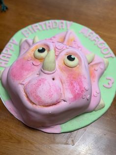 a pink and green birthday cake with an animal face