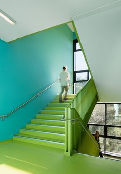 there is a man walking up the stairs in front of a green wall and blue walls