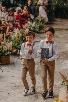 two young boys wearing suspenders and bow ties holding a book in front of an audience