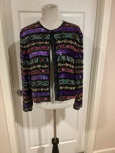 This nice 90s Nina Piccalino Sequin beaded colorblock rainbow bling cardigan jacket comes to you in a size s-m. As you can see from the pictures gold turquoise purple or pink bling jacket. Overall good used cond. pls compare the measurements given to those in your closet. Fully lined. Underarm to underarm is 18 1/2 inches underarm to underarm buttoned -22 inches shoulder to bottom of arm -21 1/2 shoulder to bottom of jacket This jacket has a couple of beads that could use some stitches, Multicolor Sequined Outerwear For Fall, Multicolor Embellished Outerwear For Winter, Fitted Multicolor Sequined Outerwear, Embellished Multicolor Outerwear For Spring, Multicolor Embellished Outerwear For Spring, Fall Multicolor Beaded Outerwear, Bild Gold, Bling Jacket, Festival Jacket