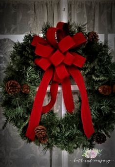 a christmas wreath with red ribbon and pine cones