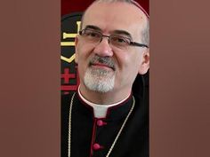 an older man wearing glasses and a priest's outfit