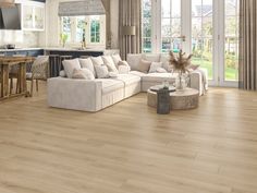 a living room filled with furniture next to a kitchen and dining room table on top of a hard wood floor