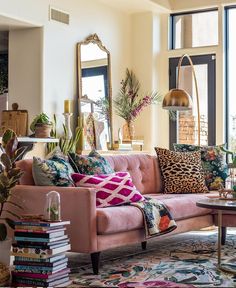 a living room filled with furniture and lots of books on top of a rug next to a window