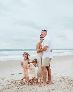 a family standing on the beach with their arms around each other