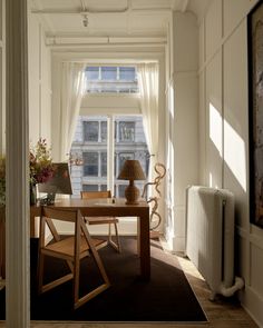 a room with a table, chair and radiator next to a window in it