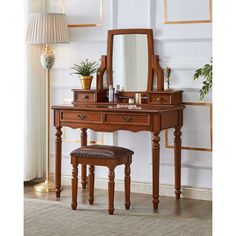 a wooden vanity with mirror, stool and potted plant