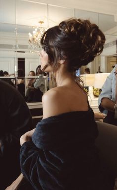 a woman sitting in a chair with her back turned to the camera, wearing a black dress