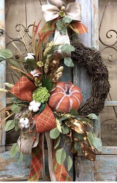 a wreath with pumpkins and greenery on the front door