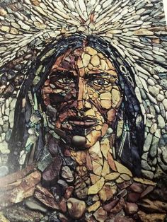 a painting made out of rocks and stones with a woman's face