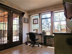 a home office with wood floors and large windows