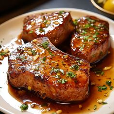 three pieces of meat on a plate with sauce and garnishes around it