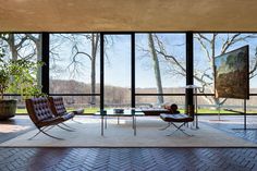 a living room with large windows overlooking the trees and grass in front of it is surrounded by brick flooring