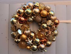 a christmas wreath hanging on the side of a white door with gold and silver ornaments