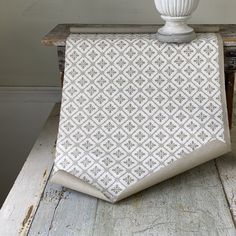 a white vase sitting on top of a wooden table