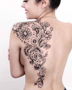 the back of a woman's shoulder with flowers and leaves tattooed on her chest