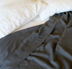 an unmade bed with two pillows on top of it and one pillow that has been folded over