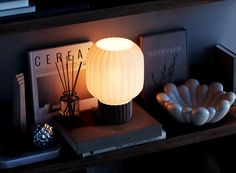 a white lamp sitting on top of a table next to books and other items in front of it