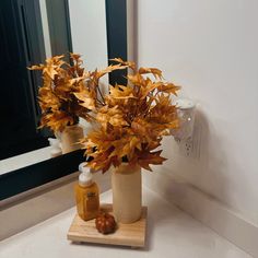 a vase filled with flowers sitting on top of a bathroom counter next to a mirror