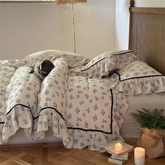 a bed with white sheets and black trim on it, next to a potted plant