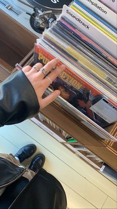 a person's hand on top of a stack of magazines in front of a black bag