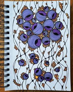 a spiral notebook with an image of purple flowers and leaves on the cover, sitting on a wooden table